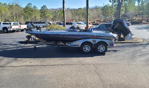 Ranger Z519 2024 Ranger Z519 boat on trailer in parking lot, surrounded by trees and vehicles.