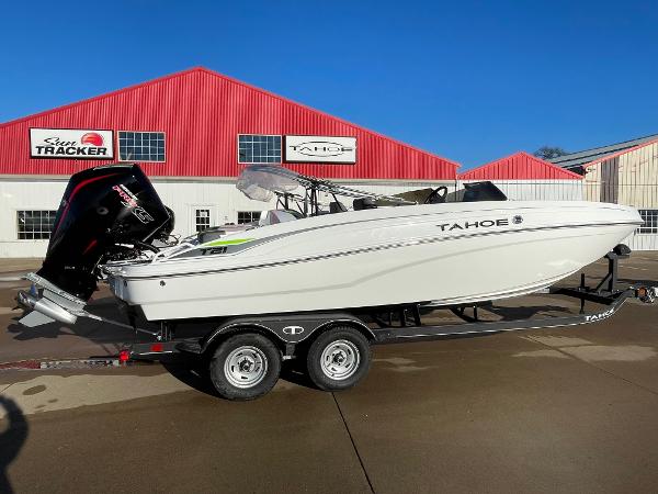 Tahoe T21 2024 Tahoe T21 boat on trailer, parked outside red building under clear blue sky.