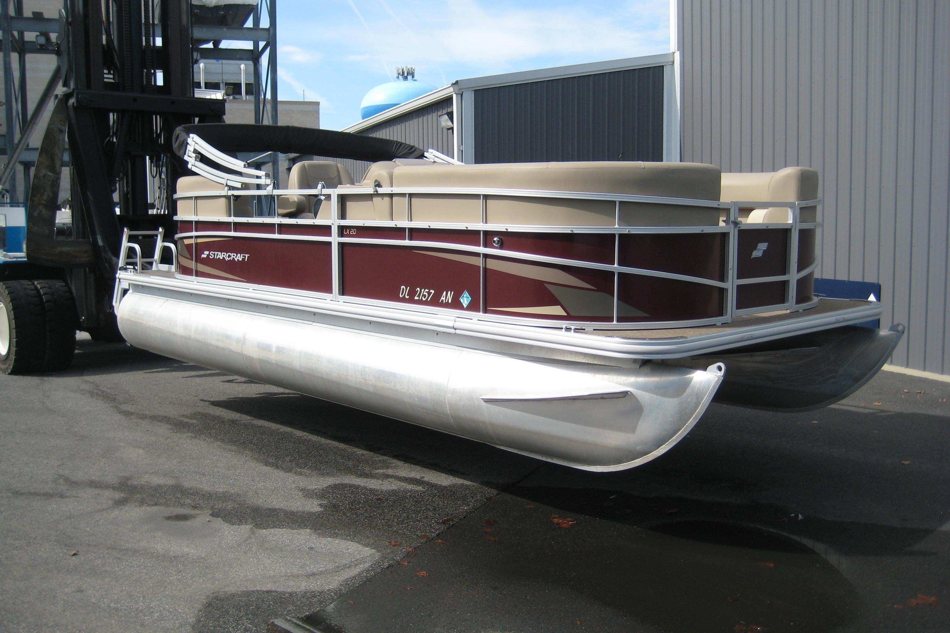 Starcraft LX 20 R 2021 Starcraft LX 20 R pontoon boat on forklift, parked near industrial building.