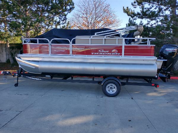 Sun Tracker Bass Buggy 18 DLX 2025 Sun Tracker Bass Buggy 18 DLX pontoon boat on trailer, parked outdoors.