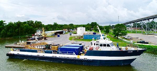 Custom C & G Boat Works High Speed Supply Vessel Custom Offshore Supply Vessel, 2002, docked near a lush riverside industrial area.