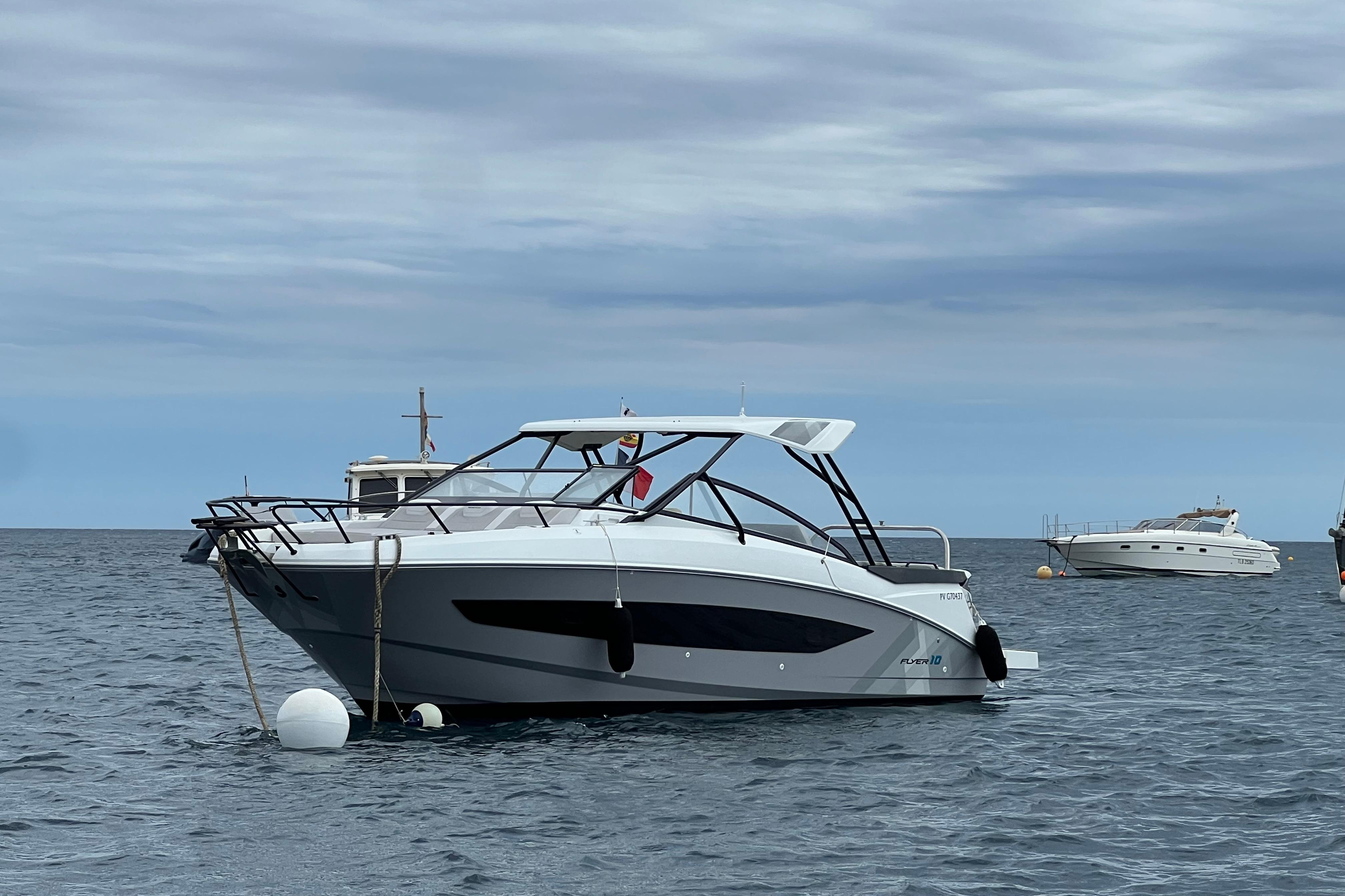 Beneteau Flyer 10 2024 Beneteau Flyer 10 boat anchored on calm sea under cloudy sky.