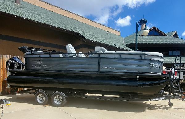 Regency 230 DL3 2023 Regency 230 DL3 pontoon boat on a trailer, parked outdoors.