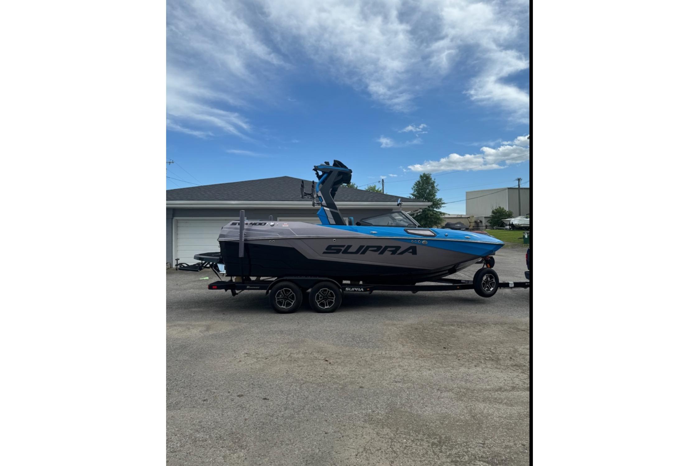 Supra SV 400 2024 Supra SV 400 boat on trailer, parked outdoors under a partly cloudy sky.