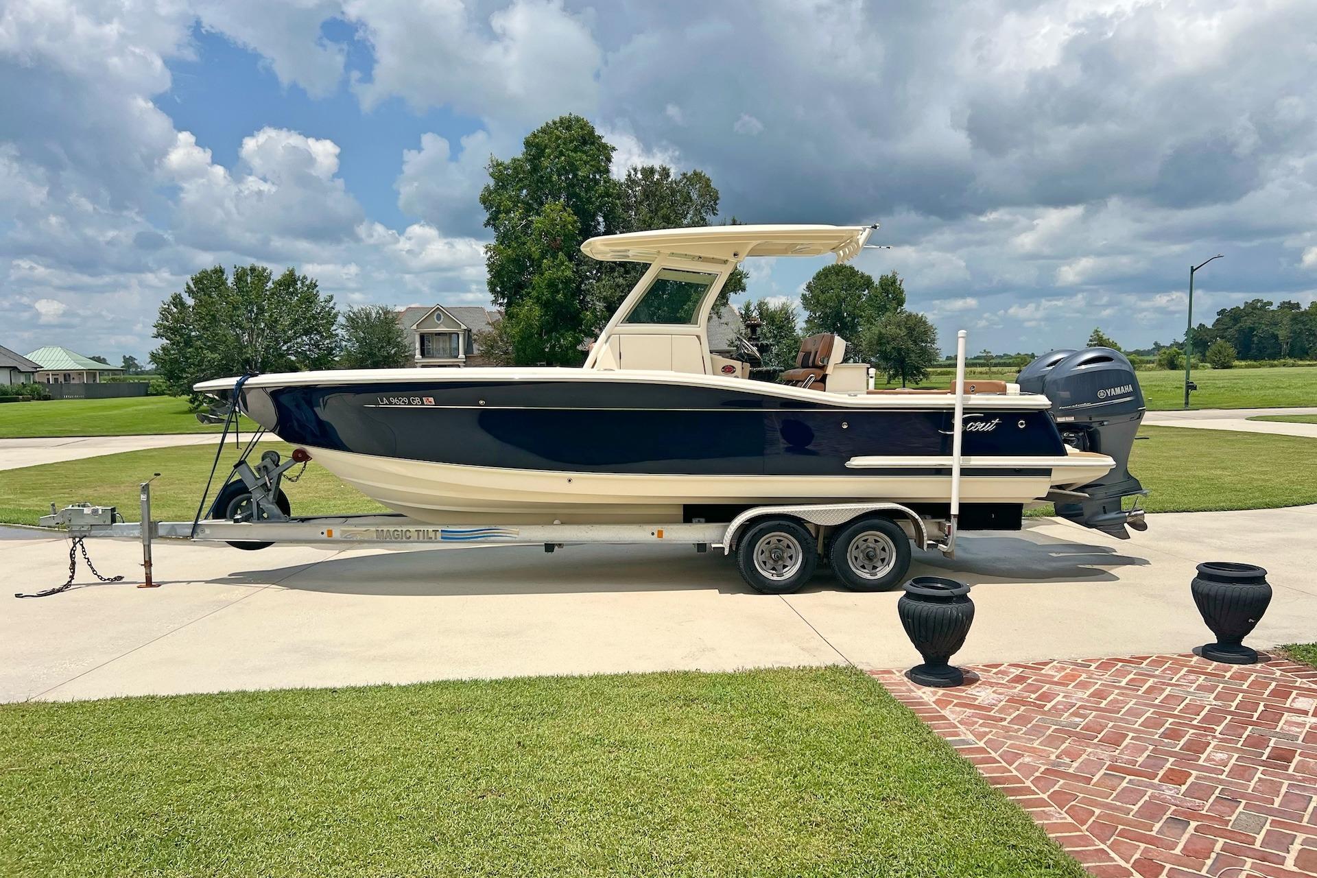 Scout 275 LXF 2014 Scout 275 LXF boat on trailer, parked in a driveway under cloudy sky.