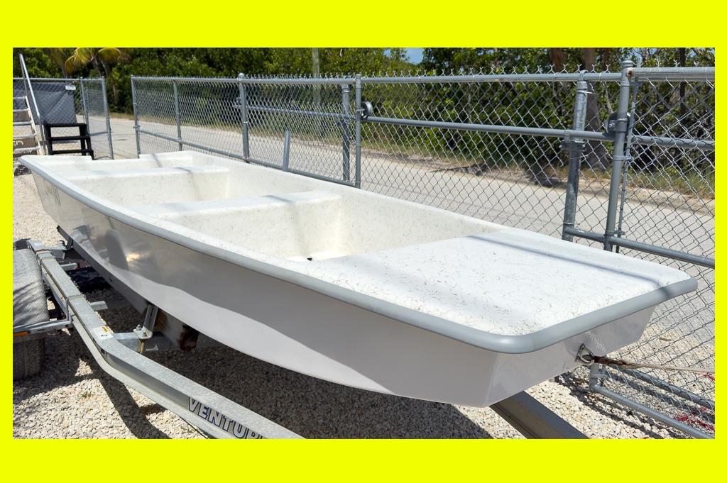 Coastal Skiff 145 2026 Coastal Skiff 145 boat on trailer, parked near chain-link fence.