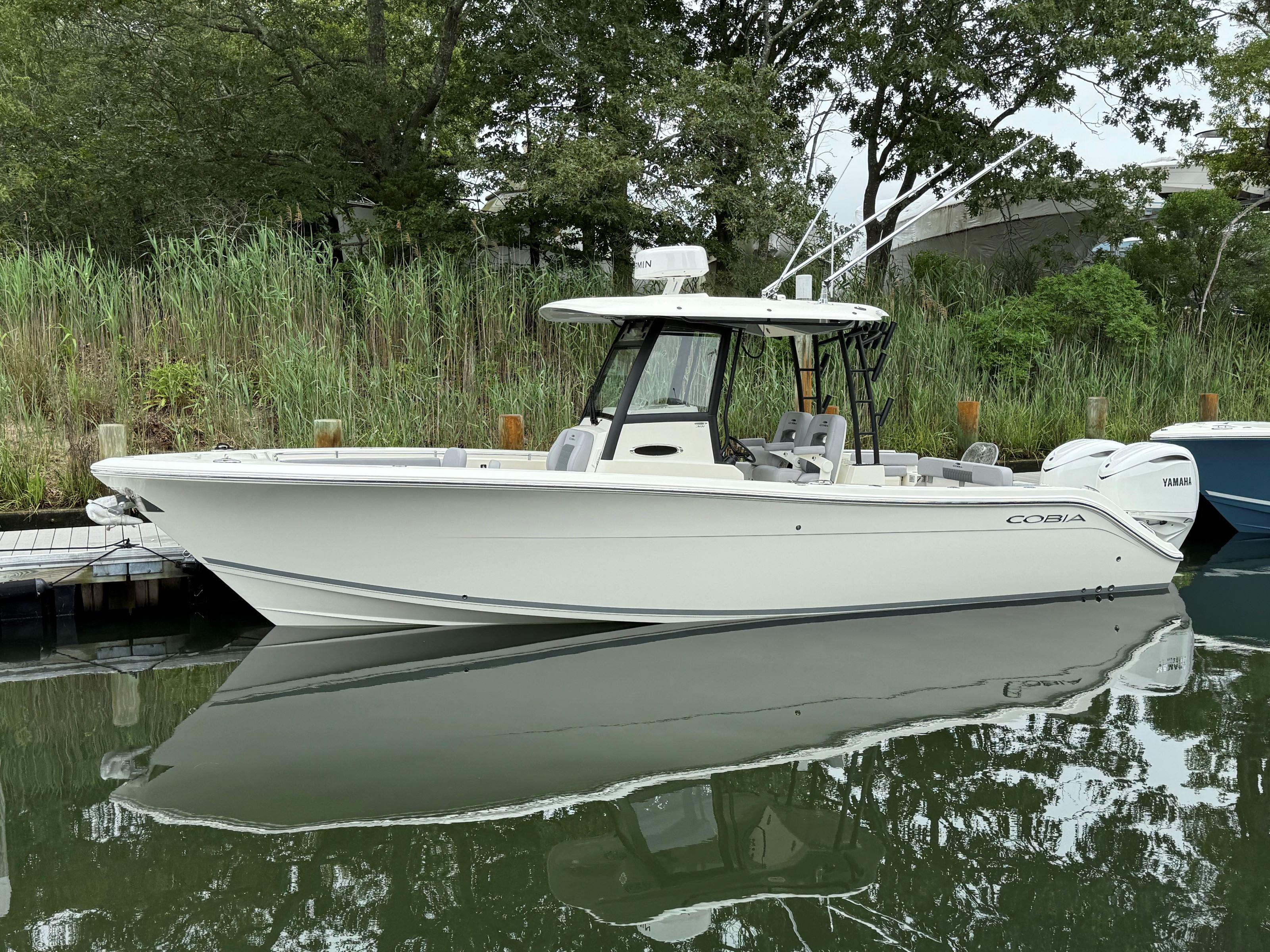 Cobia 301 Center Console 2025 Cobia 301 Center Console boat docked by lush greenery.