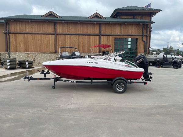Tahoe T16 2025 Tahoe T16 boat with red hull on trailer, parked near wooden building.