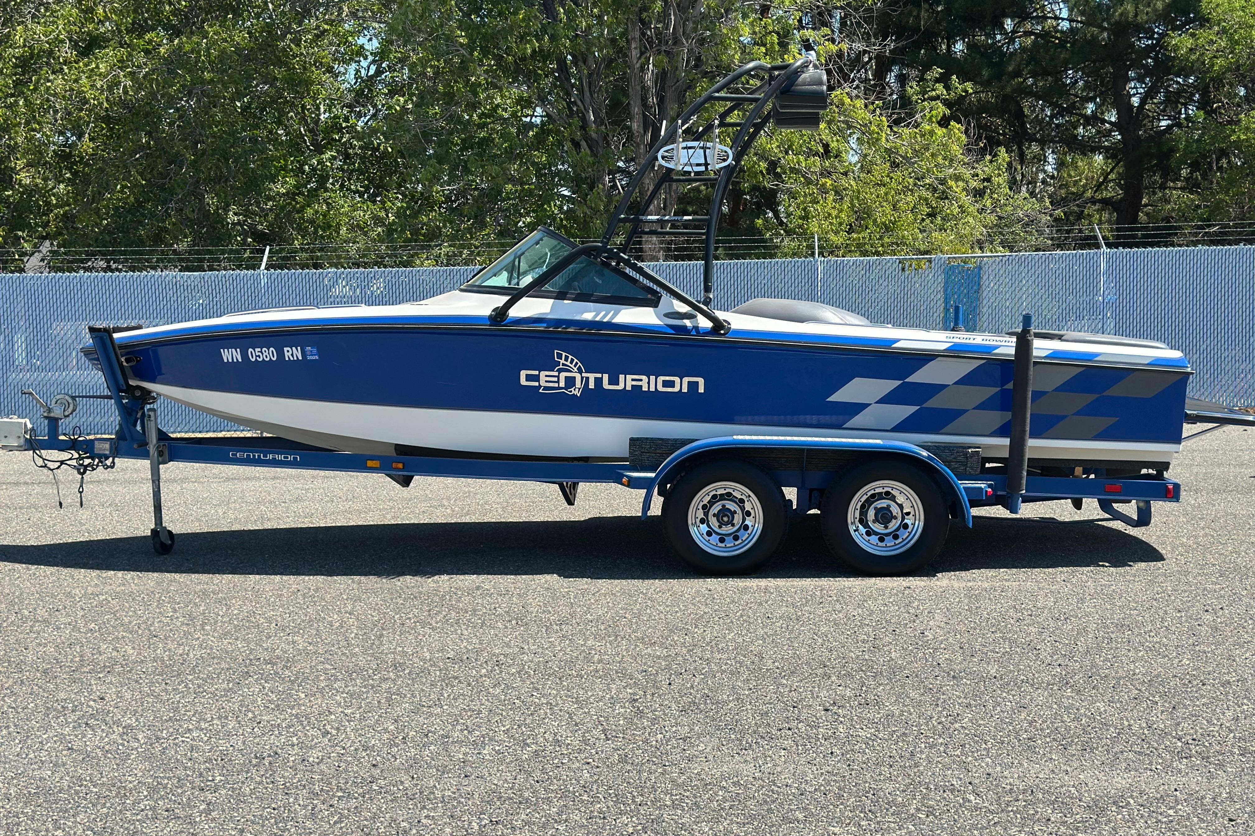Centurion Elite Bowrider 2001 Centurion Elite Bowrider boat on trailer, blue and white design, parked outdoors.
