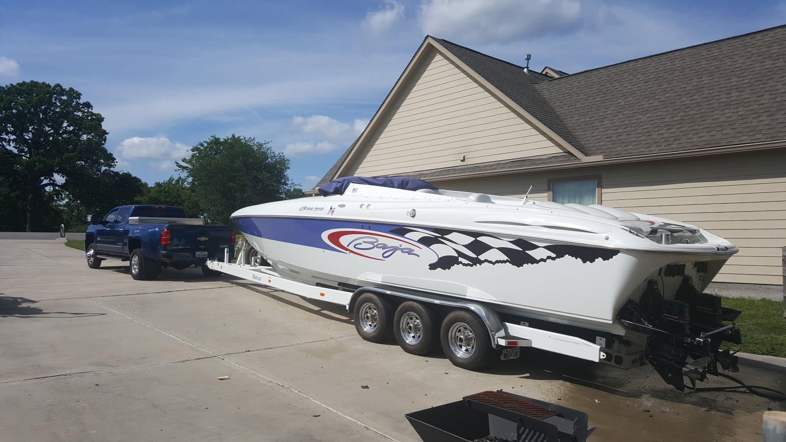 Baja 342 2001 Baja 342 boat on trailer, parked beside a house, with a blue truck.