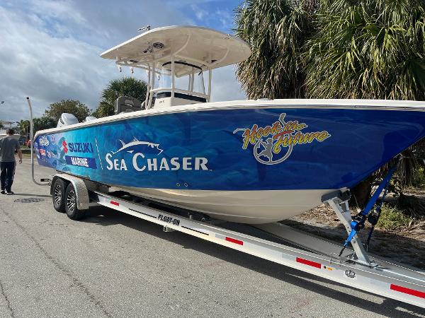 Sea Chaser 30 HFC CC 2025 Sea Chaser 30 HFC CC boat on trailer, blue design, parked near palm trees.