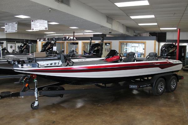 Skeeter ZXR21SE 2025 Skeeter ZXR21SE bass boat displayed in showroom, featuring sleek design and dual-axle trailer.