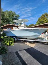 Sailfish 220 CC 2022 Sailfish 220 CC boat on trailer, parked in driveway, surrounded by greenery and blue sky.