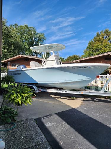 Sailfish 220 CC 2022 Sailfish 220 CC boat on trailer, parked in driveway, surrounded by greenery and blue sky.
