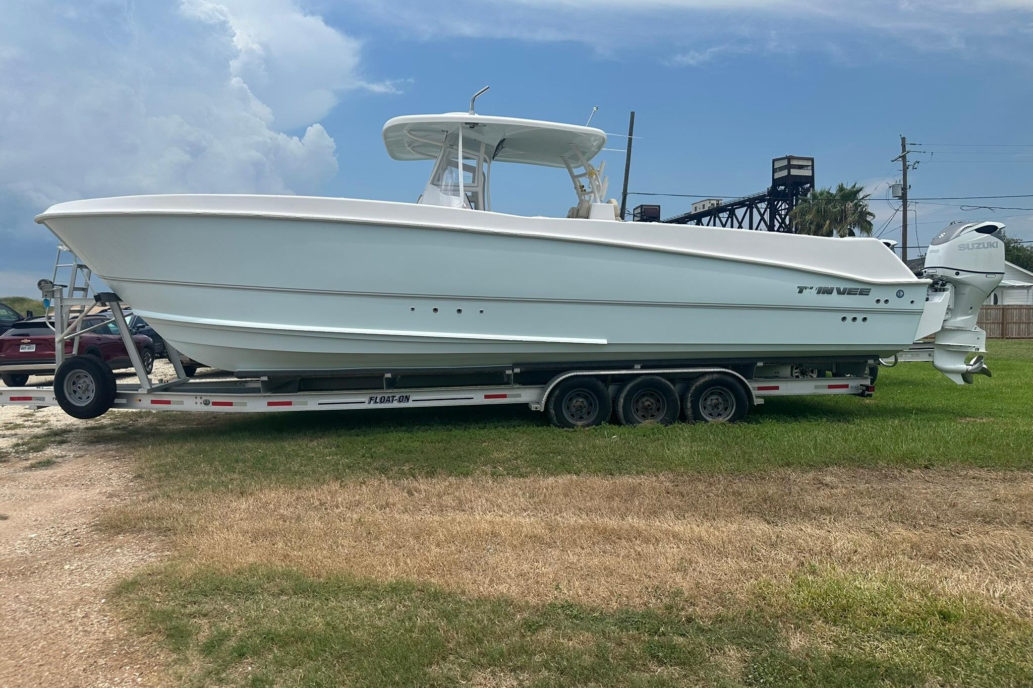 Twin Vee 340 GFX CC 2023 Twin Vee 340 GFX CC boat on trailer, parked on grass under cloudy sky.