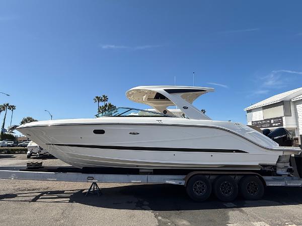 Sea Ray SLX 310 Outboard 2025 Sea Ray SLX 310 OB boat on trailer, sunny day, palm trees in background.