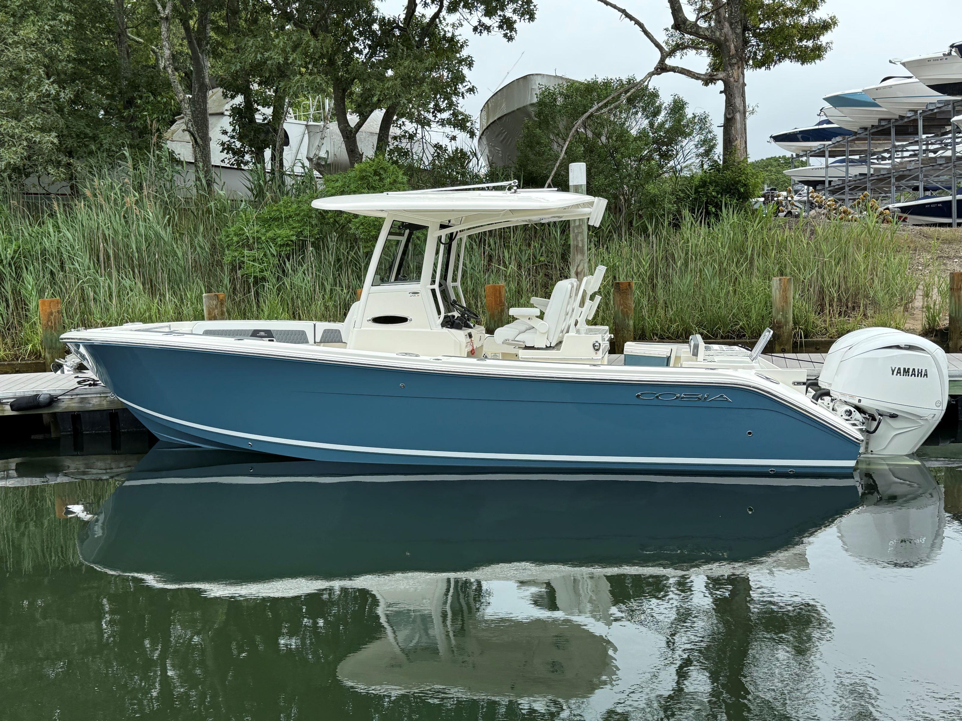 Cobia 265 Open Center Console 2025 Cobia 265 Open Center Console boat docked, featuring Yamaha engine, surrounded by greenery.