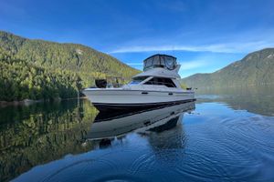 Bayliner 3388 Command Bridge Motoryacht Bayliner 3388 Command Bridge Motoryacht 1999 on serene lake with forested mountains.