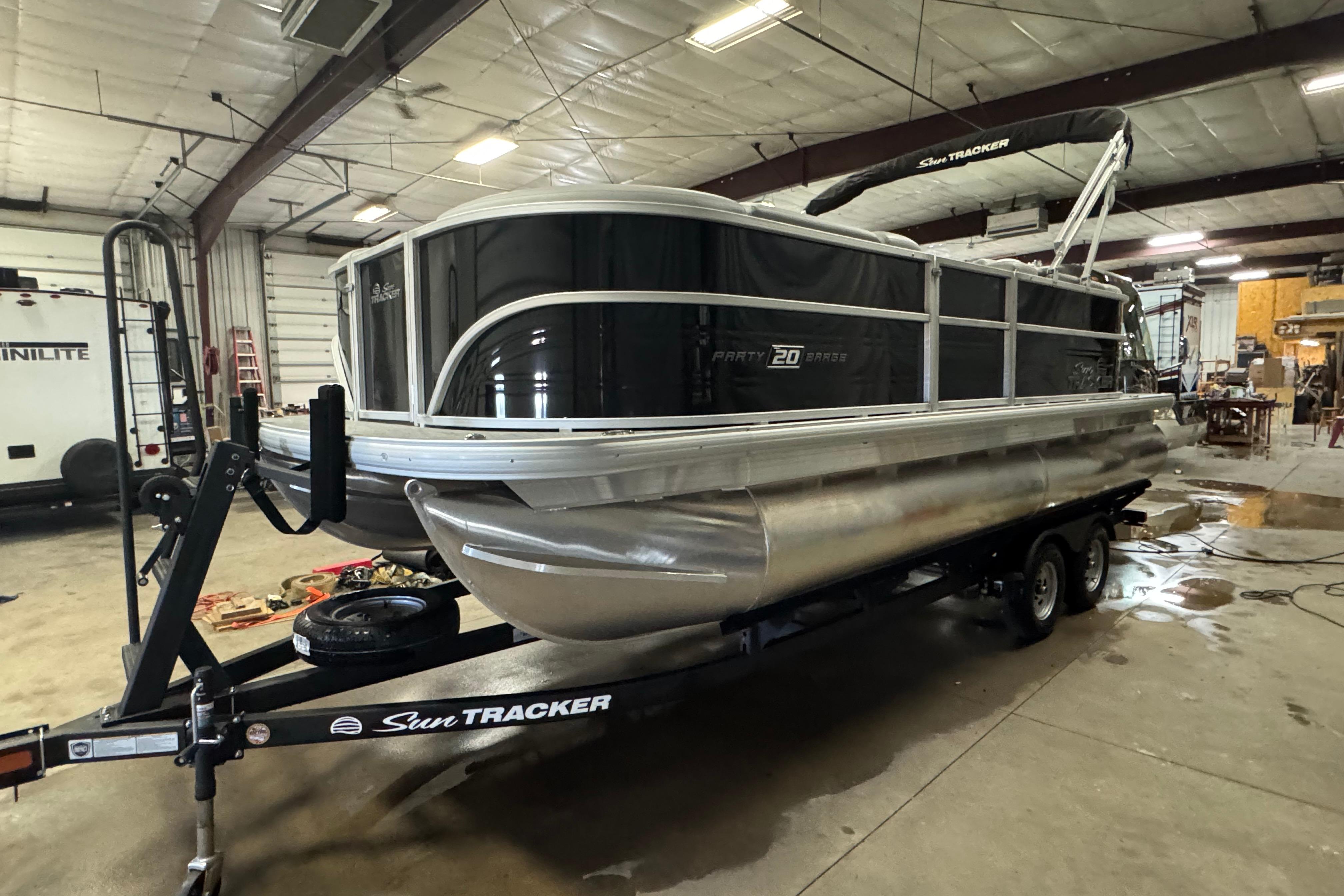 Sun Tracker Party Barge 20 DLX 2026 Sun Tracker Party Barge 20 DLX pontoon boat in a garage setting.