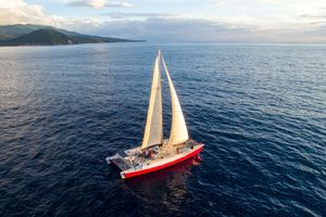 Catamaran Day Charter Open Bridge Deck Red 1995 Catamaran Day Charter sailing on open sea with scenic coastline.