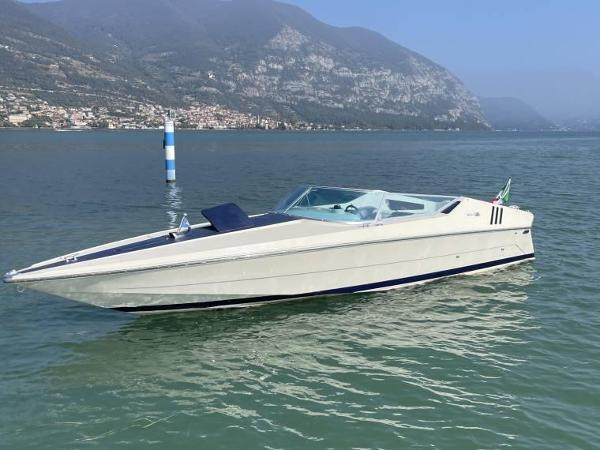 Riva St Tropez 1972 Riva St. Tropez boat on a serene lake with mountainous backdrop.