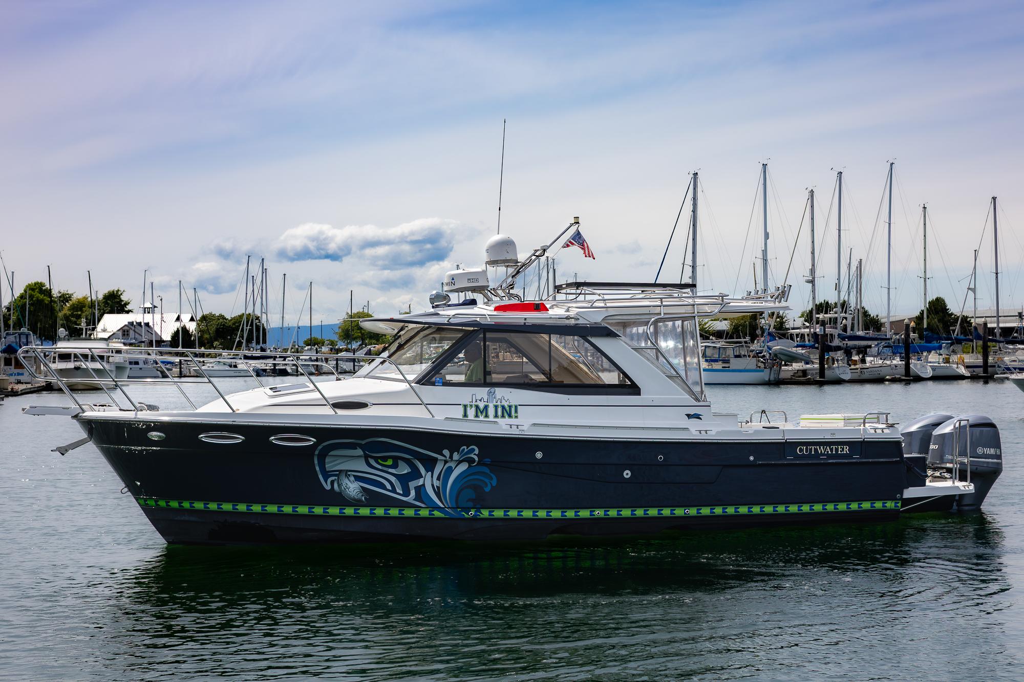 Cutwater C-302 Sport Coupe 2017 Cutwater C-302 Sport Coupe boat docked in marina, featuring custom graphics.