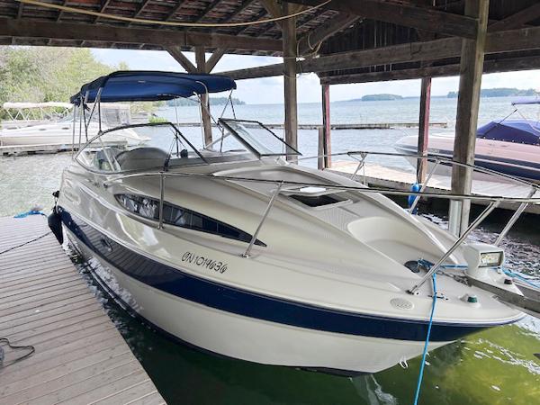 Bayliner 245 CIERA 2003 Bayliner 245 CIERA boat docked under a wooden shelter by the lake.