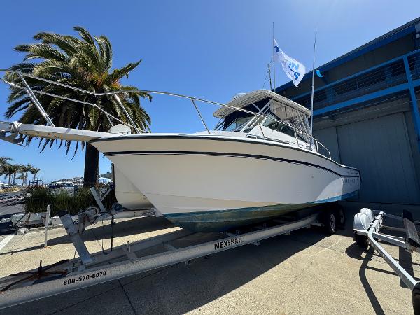 Grady-White Marlin 28 1990 Grady-White Marlin 28 boat on trailer, parked near palm trees and building.