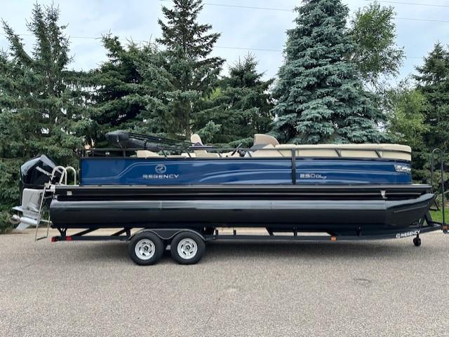 Regency 250 DL3 2023 Regency 250 DL3 pontoon boat on trailer, parked near trees.