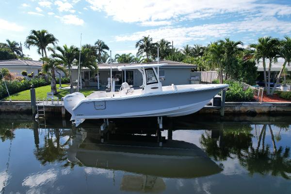 Sea Hunt Ultra 275 SE 2024 Sea Hunt Ultra 275 SE boat docked by waterfront home with palm trees.