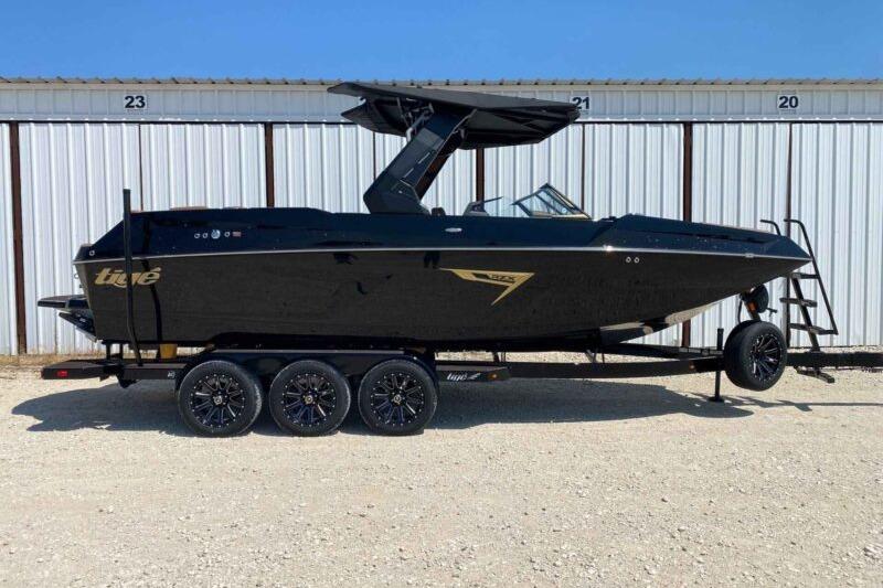 Tigé 24RZX 2026 Tigé 24RZX boat on trailer, sleek black design, parked outdoors.