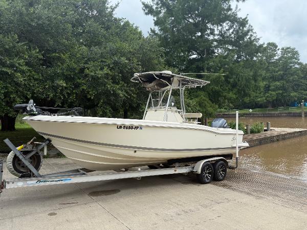 Scout 235 Sportfish 2002 Scout 235 Sportfish boat on trailer near water, surrounded by trees.