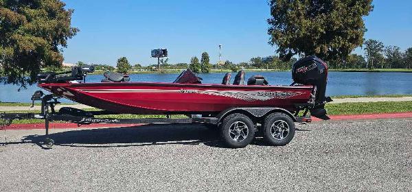 Ranger RT188P 2024 Ranger RT188P boat in red, parked by a lake on a sunny day.