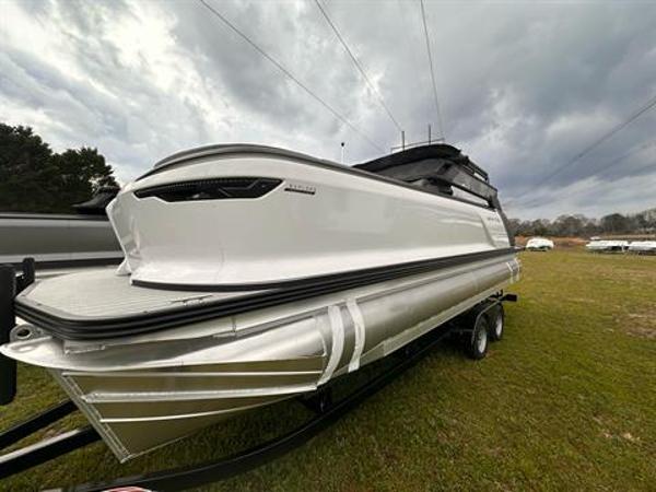 Manitou 24 Explore 2024 Manitou 24 Explore pontoon boat on a trailer under cloudy skies.