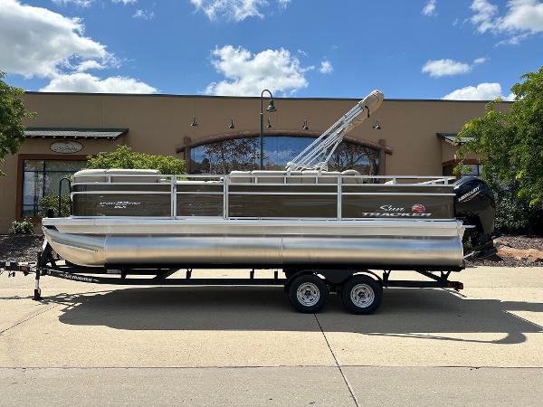 Sun Tracker SportFish 22 DLX 2024 Sun Tracker SportFish 22 DLX pontoon boat on trailer, parked outdoors.