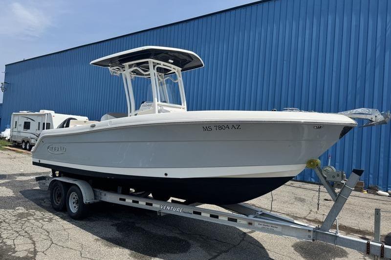 Robalo R242 2021 Robalo R242 boat on trailer, parked near a blue building.