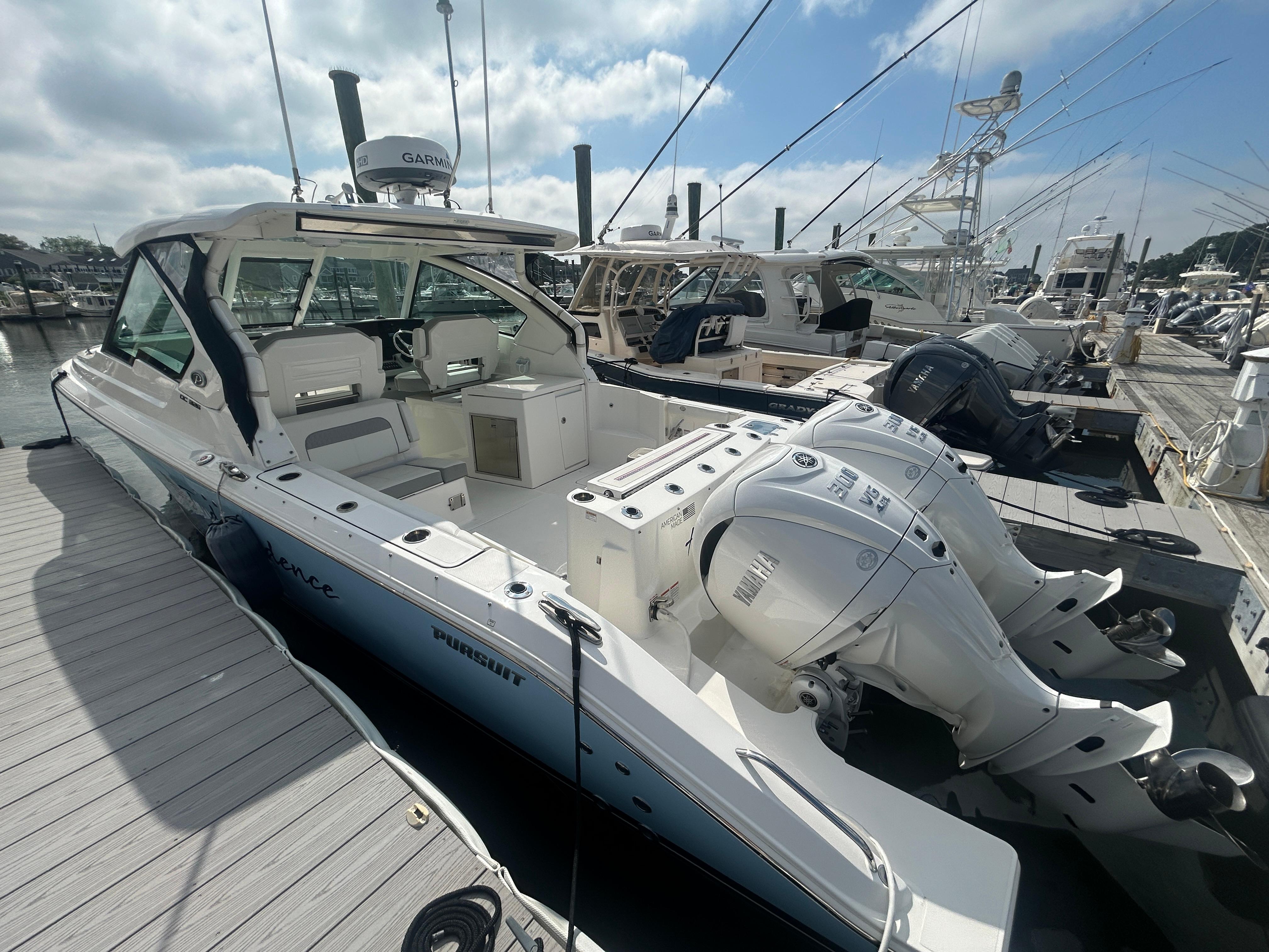 Pursuit DC 326 Dual Console 2023 Pursuit DC326 boat docked, featuring dual outboard engines and spacious seating.