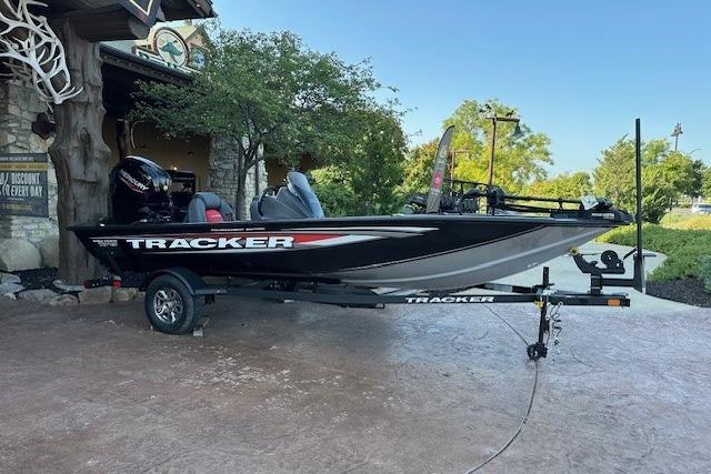 Tracker Pro Team 175 2025 Tracker Pro Team 175 boat on trailer, parked outdoors near trees.