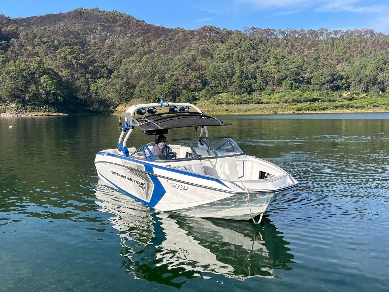 Nautique Super Air Nautique G25 2016 Nautique Super Air Nautique G25 boat on a serene lake with forested hills.