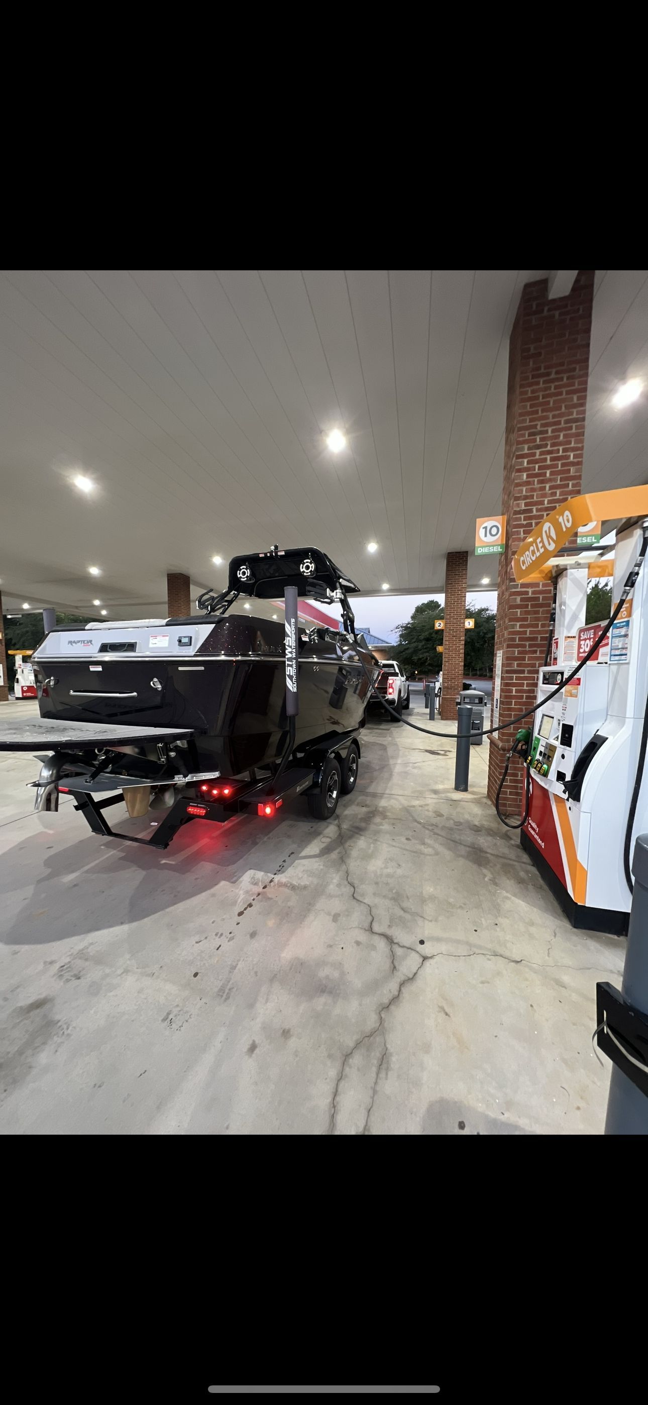 Moomba Max 2023 Moomba Max boat on trailer at gas station, rear view.