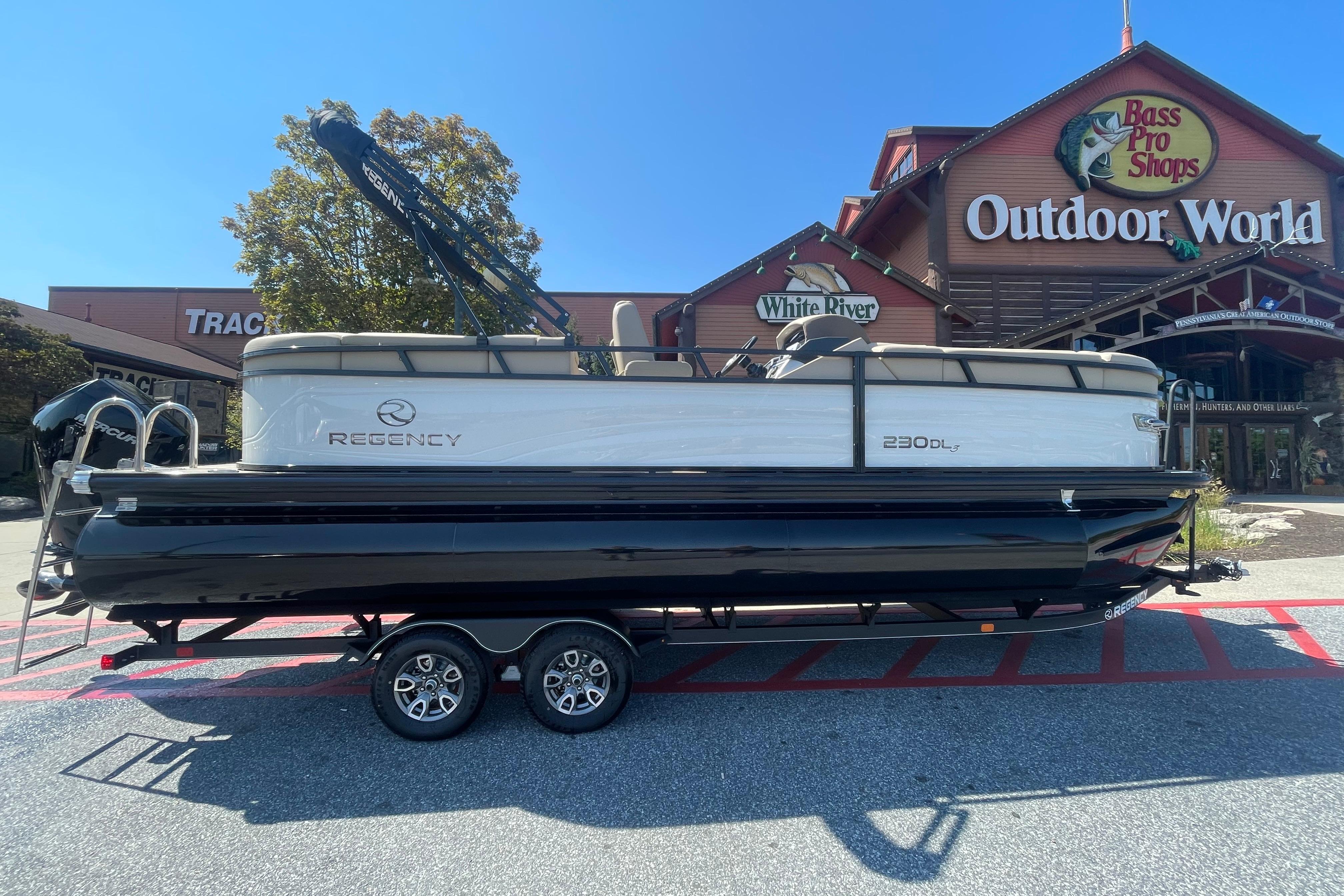 Regency 230 DL3 2025 Regency 230 DL3 pontoon boat displayed outside Bass Pro Shops Outdoor World.