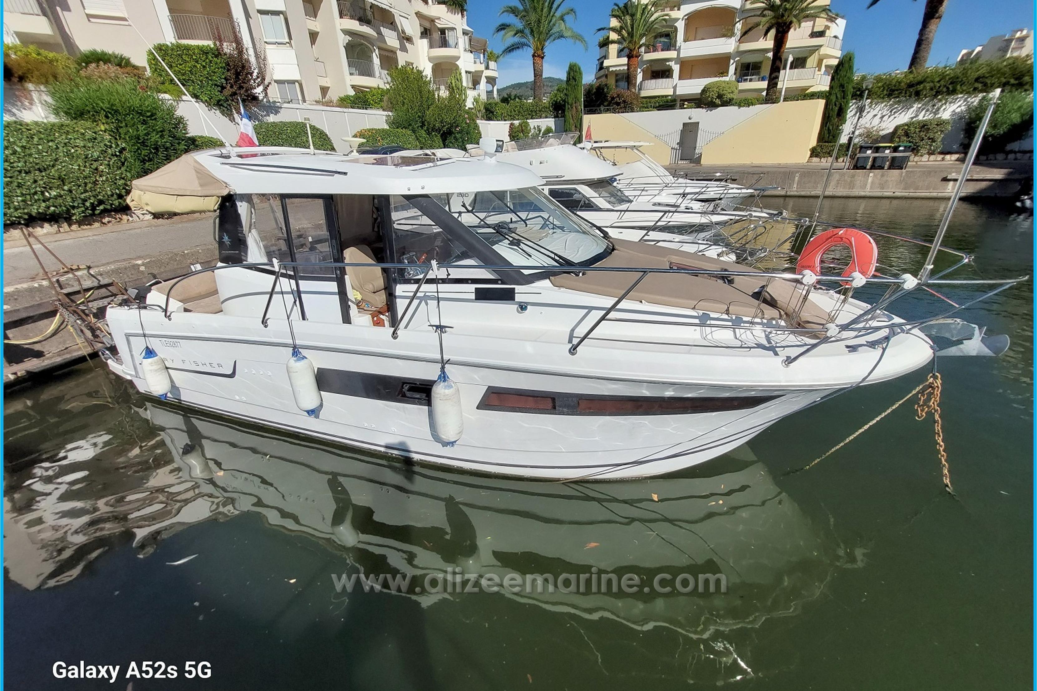 Jeanneau Merry Fisher 855 2014 Jeanneau Merry Fisher 855 boat docked in a marina, surrounded by modern buildings.