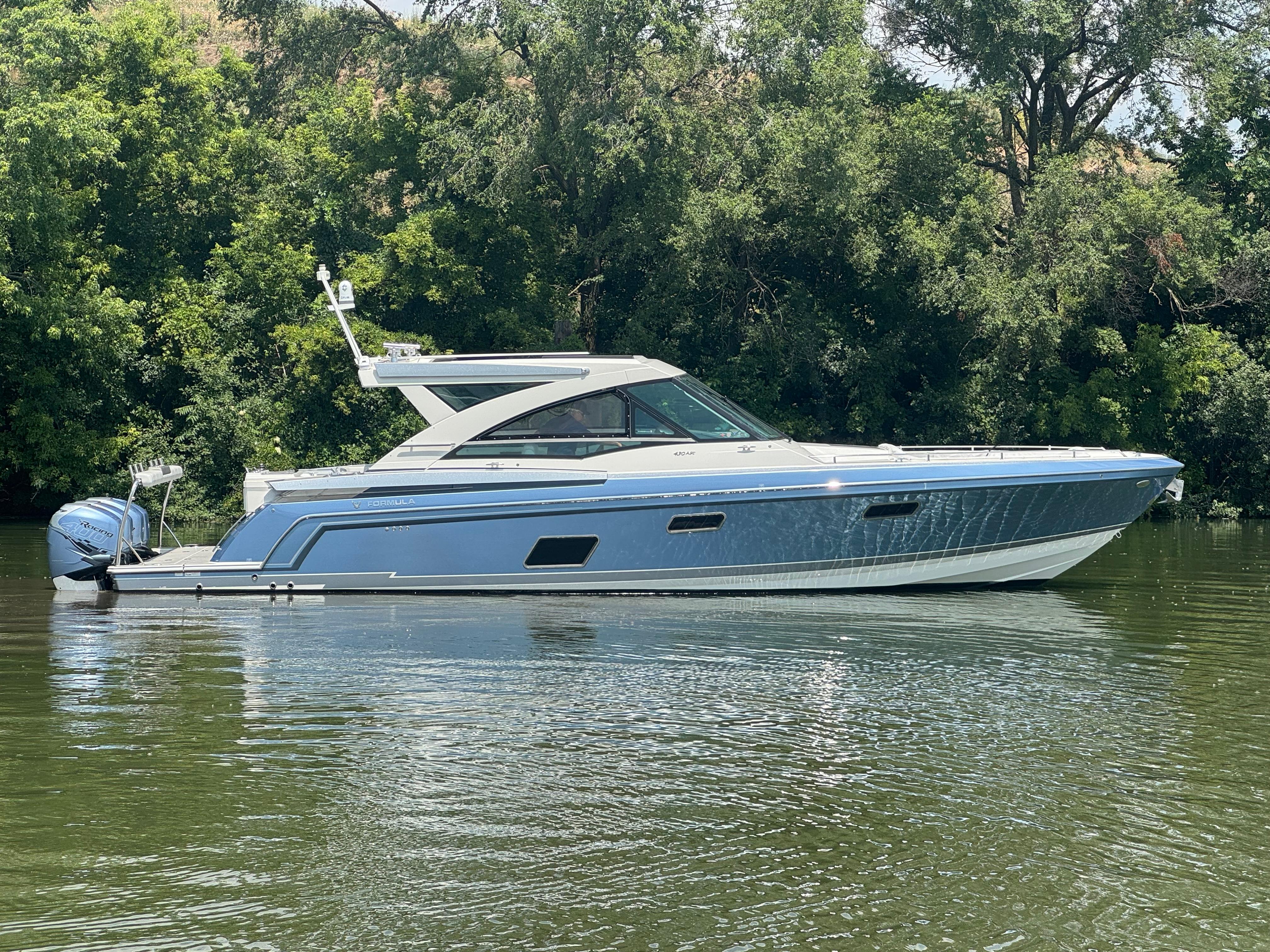 Formula 430 All Sport Crossover 2019 Formula 430 All Sport Crossover boat on calm water, surrounded by lush greenery.