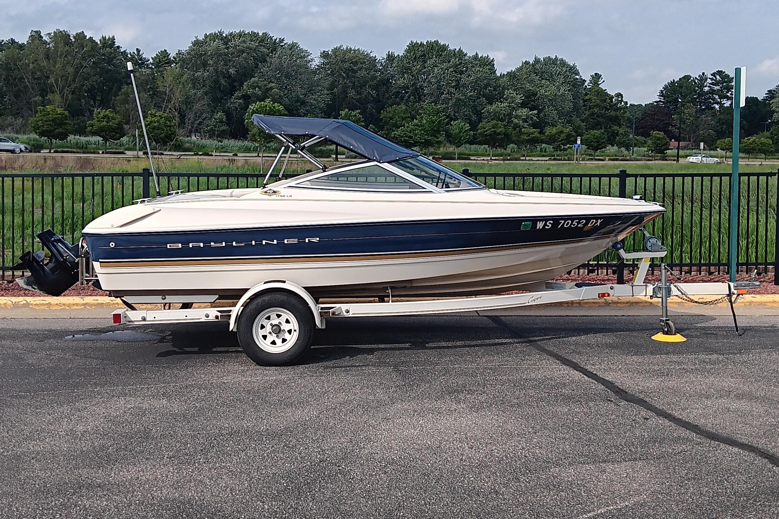 Bayliner 1750 Capri LSV 1996 Bayliner 1750 Capri LSV boat on trailer, parked outdoors near greenery.