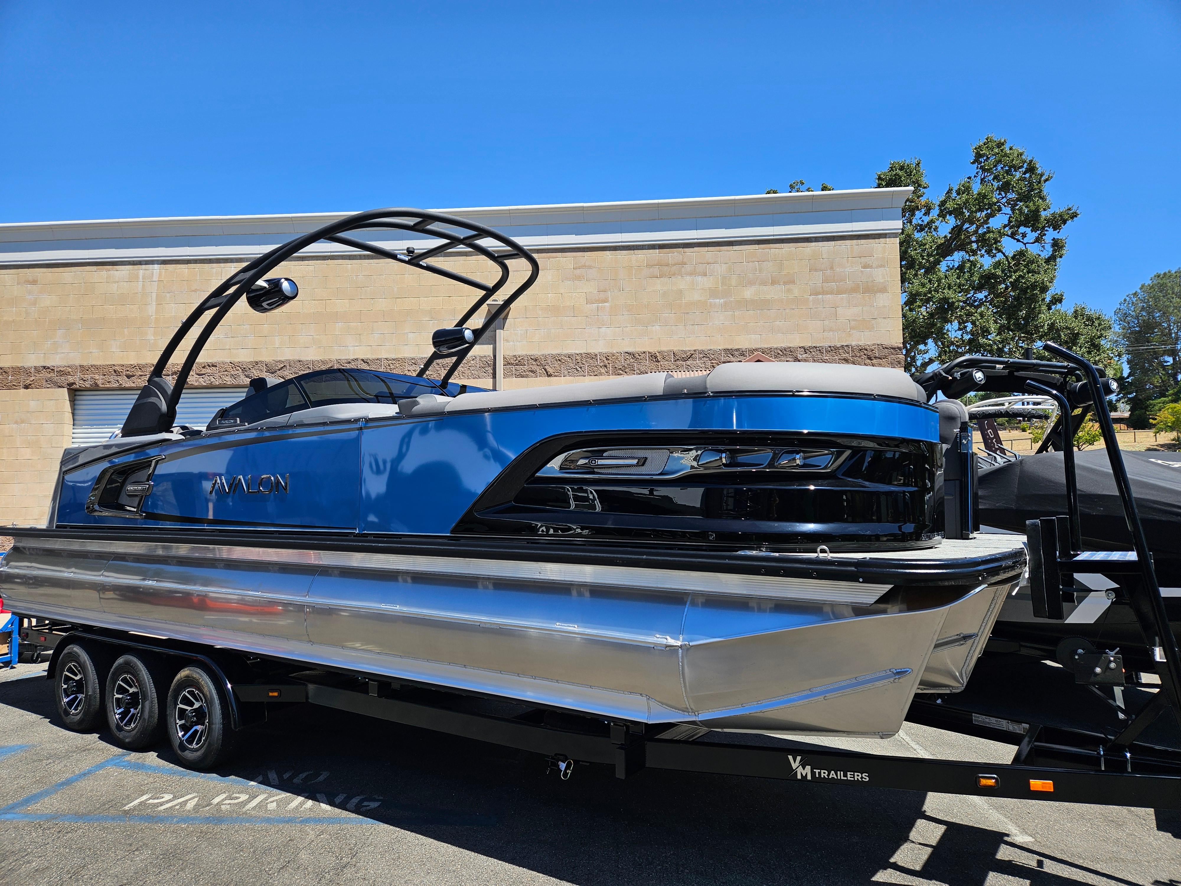 Avalon Excalibur LTD Elite Windshield 27FT 2025 Avalon Excalibur LTD Elite Windshield 27FT boat on trailer, blue and silver design.