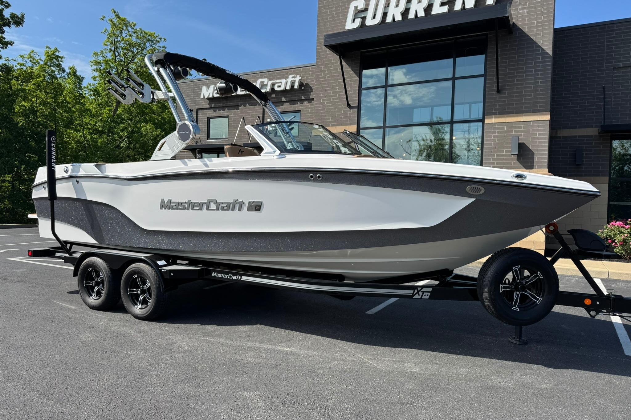 MasterCraft XT24 2025 MasterCraft XT24 boat on trailer, parked outside dealership.