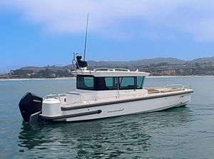 Axopar 28 2022 Axopar CABIN WETBAR boat on calm water with scenic background.