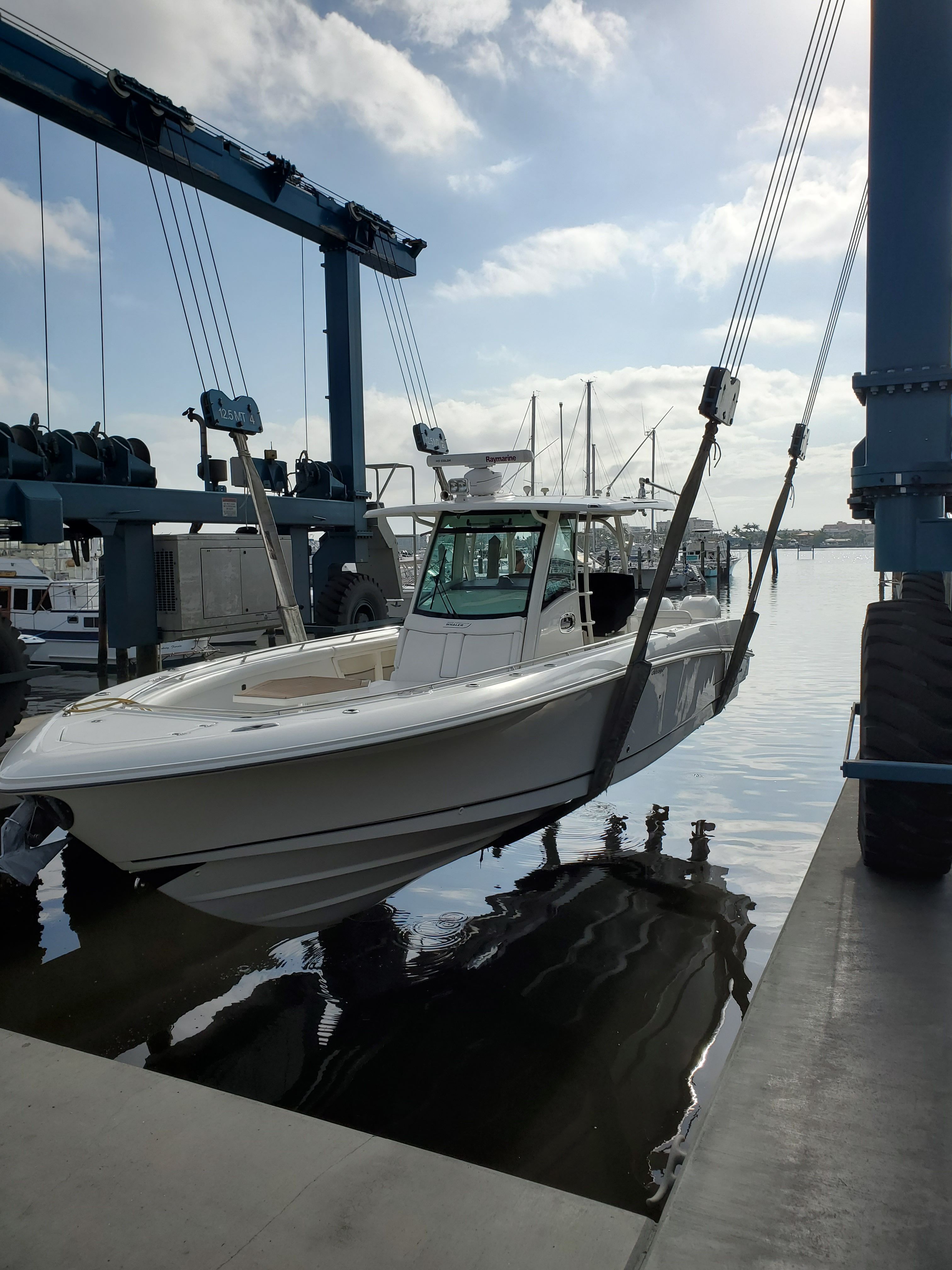 Boston Whaler 350 Outrage 2015 Boston Whaler 350 Outrage being lifted at a marina under a clear sky.