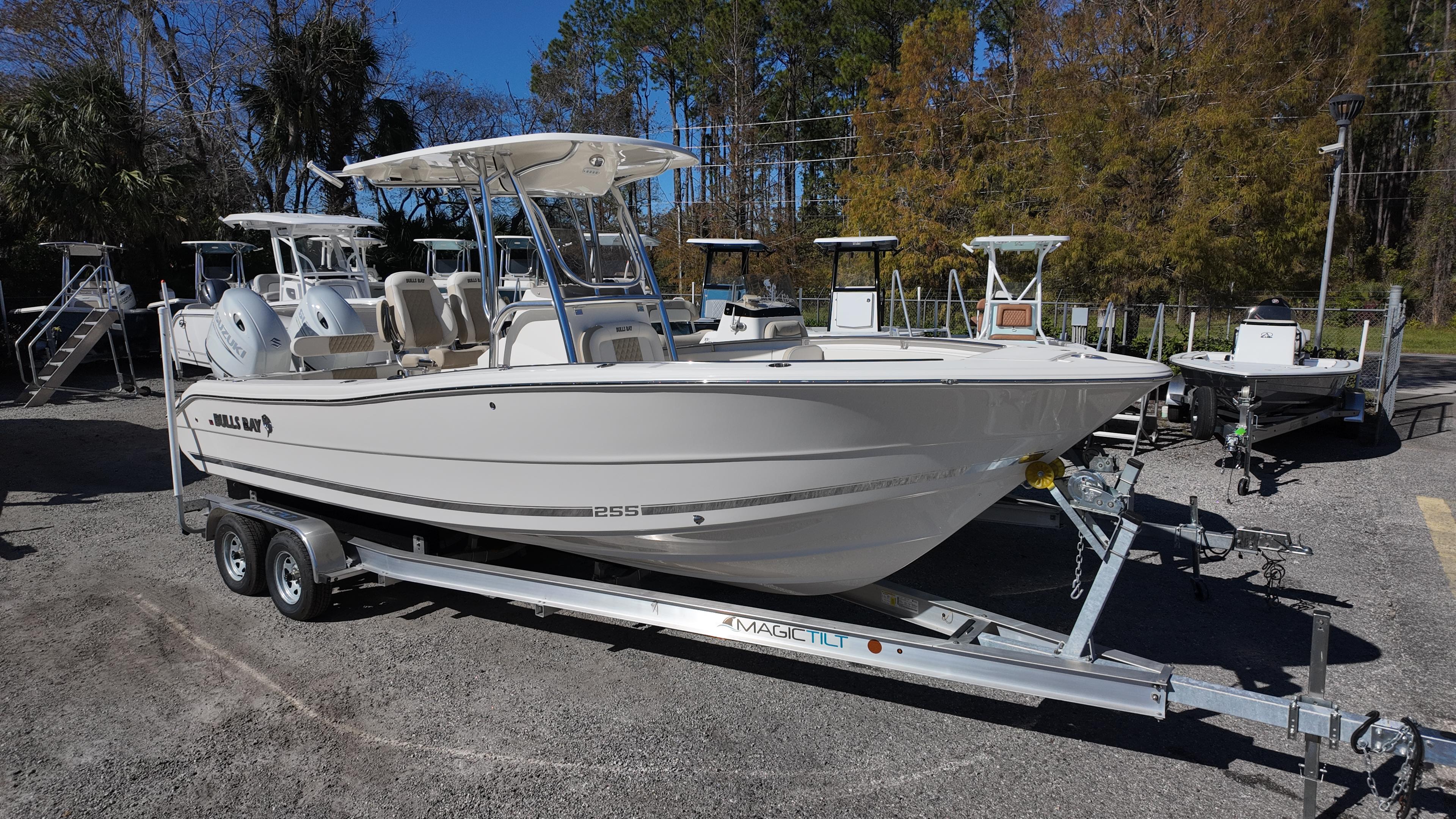 Bulls Bay 255 2025 Bulls Bay 255 boat on trailer, parked outdoors, surrounded by trees and other boats.