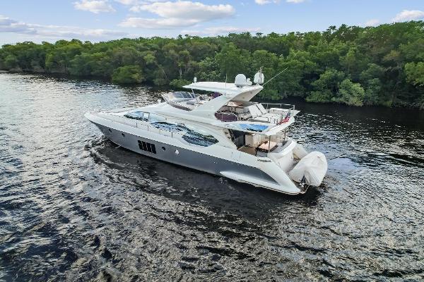 Azimut 70 2013 Azimut 70 yacht cruising on a serene river with lush green trees in the background.